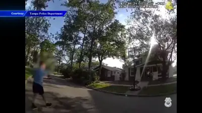 Tampa police officer helps child practice basketball